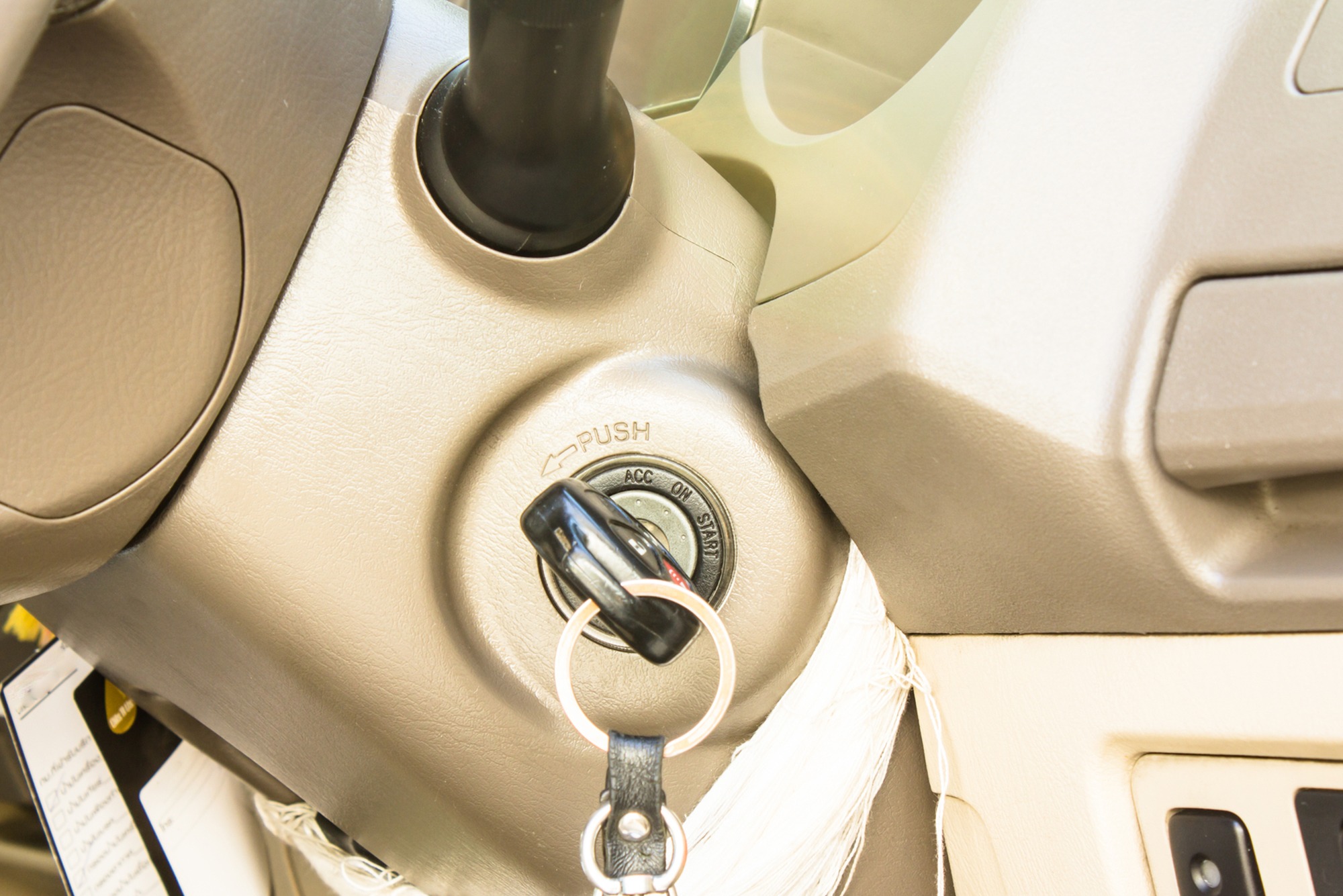 Ignition switch with key in a vehicle's dashboard, highlighting the "PUSH" start function. Relevant for discussions on car starting mechanisms.
